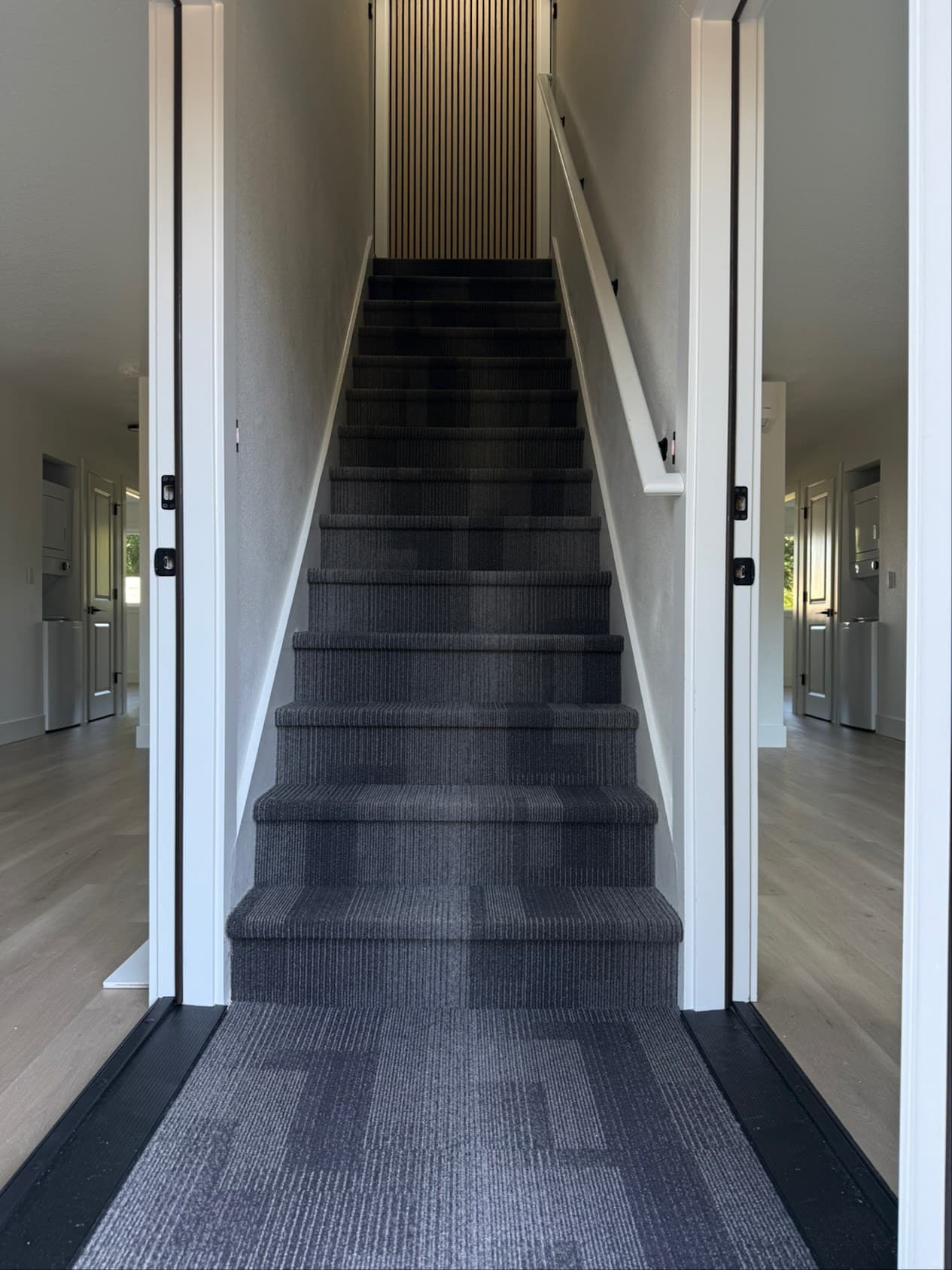 Dark gray carpet tile installation on stairs with LVP flooring visible on either side — Skyview Flooring duplex project in Vancouver, WA