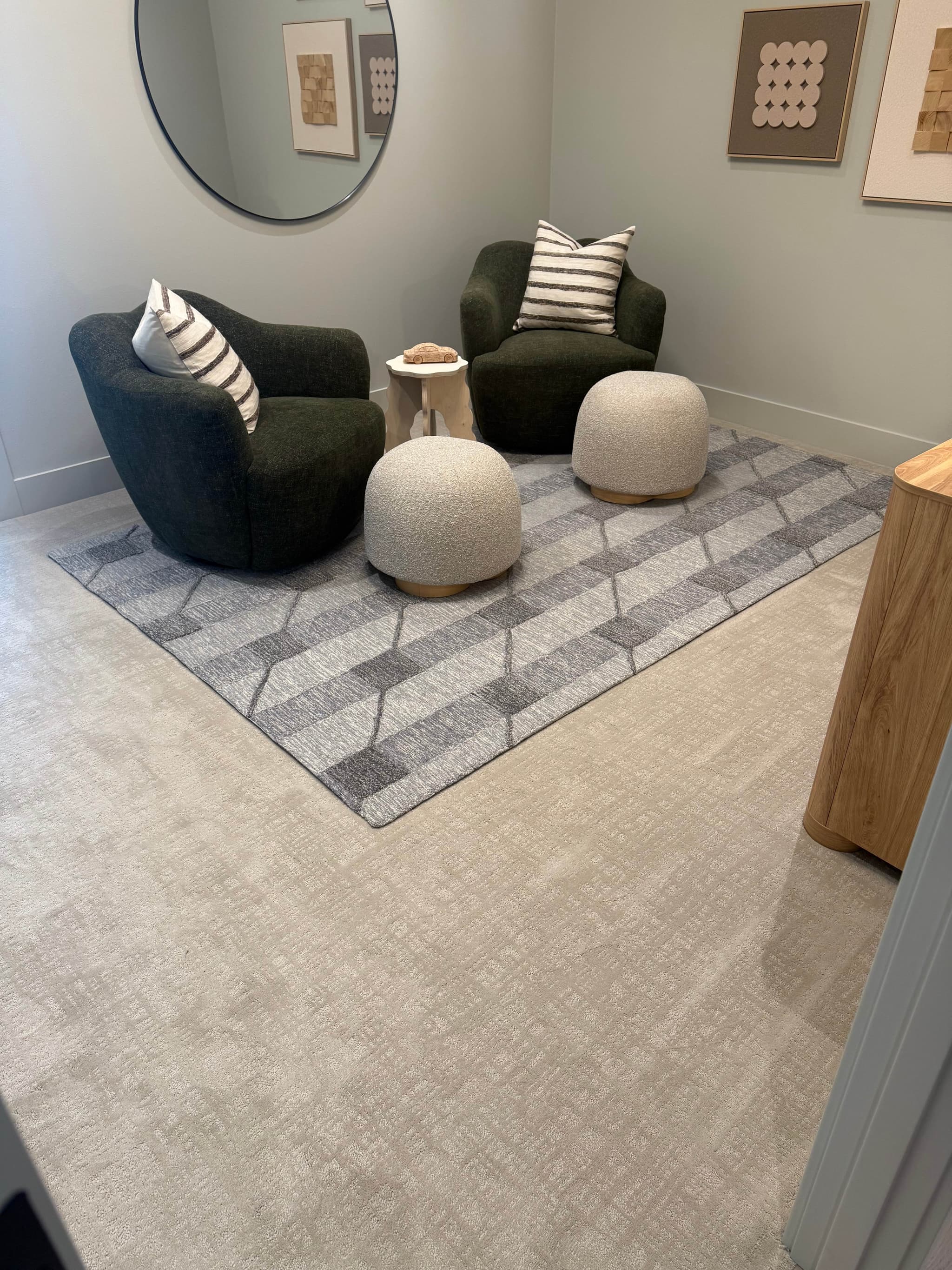 Plush textured cream carpet installation in a cozy lounge with dark green swivel chairs, boucle poufs, and a gray geometric area rug — Skyview Flooring project in Bethany, OR