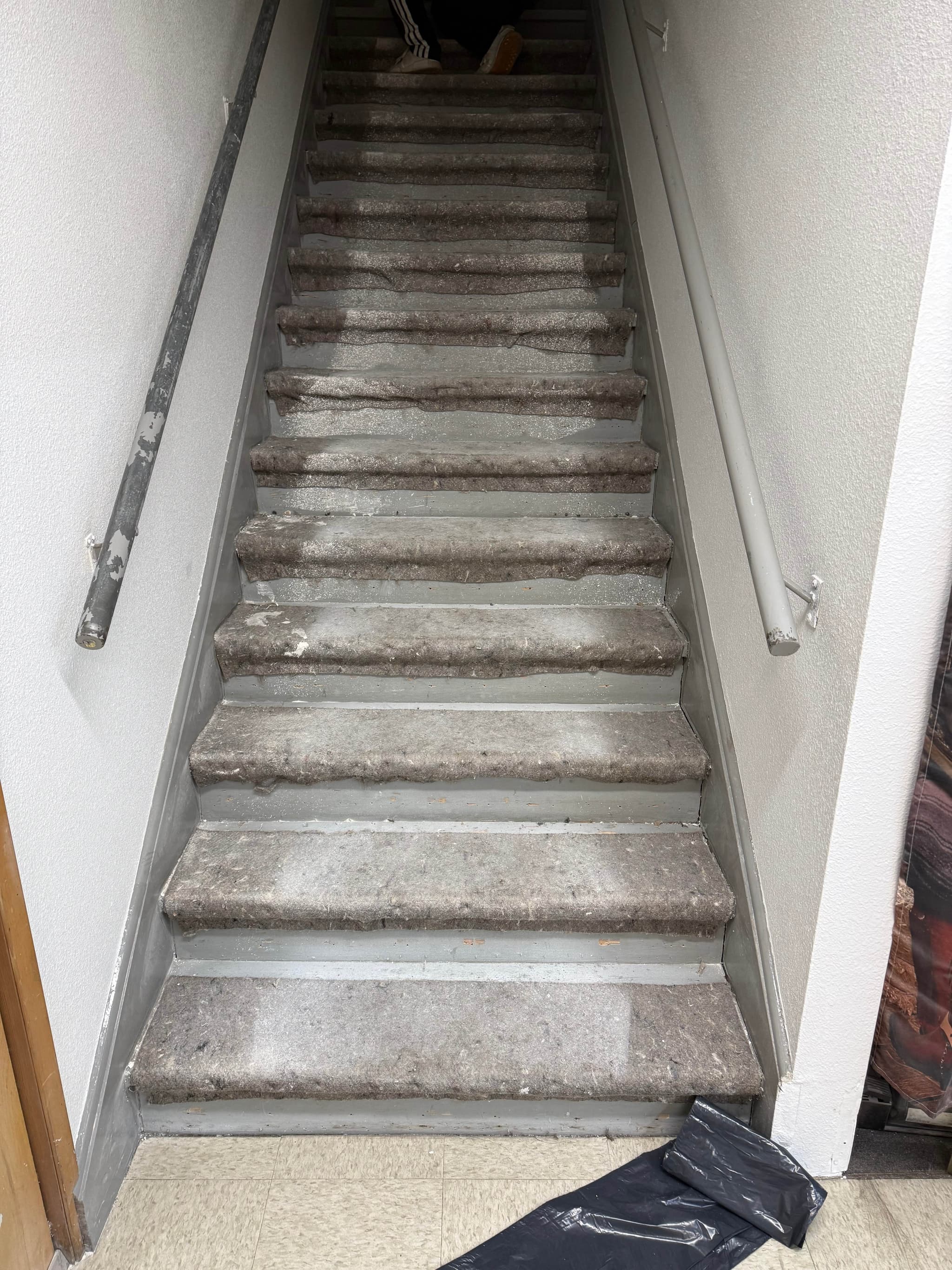 Worn carpet and padding removed from Andersen Dairy's office stairwell in Battle Ground, WA, exposing the bare stair treads before replacement