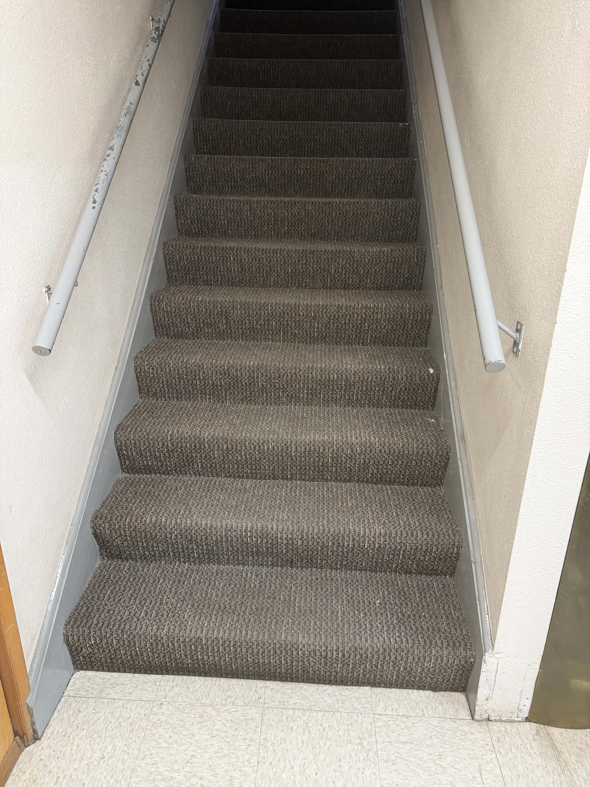 Old carpet on Andersen Dairy's office stairwell in Battle Ground, WA, installed with the waterfall method, draped over each stair nose