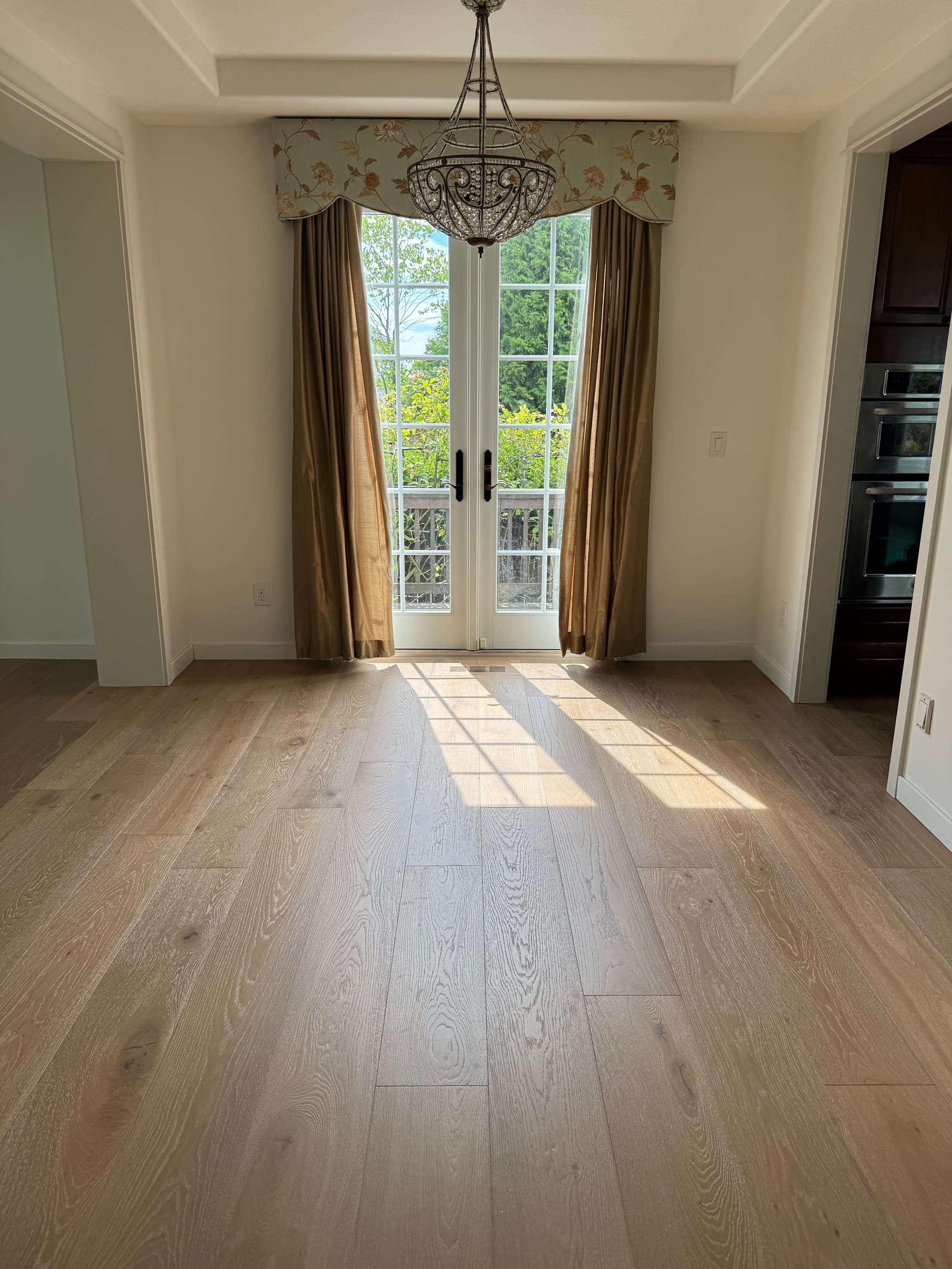 Sunlight across engineered hardwood flooring in a Ridgefield, WA dining room with french doors and a chandelier